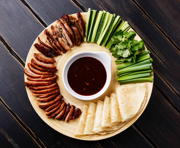 北京烤鸭配鲜黄瓜, 大葱, 香菜和烤面食, hoysin 酱在黑色木质背景下