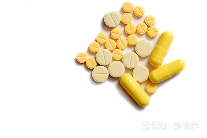 在孤立的白色背景上的黄色片剂特写。不同形状和大小的片剂。白色背景上的黄色棕色和橙色隔离