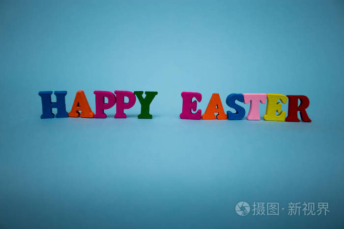 快乐的复活节文本从彩色木质字母孤立的蓝色背景。复活节快乐。节日装饰