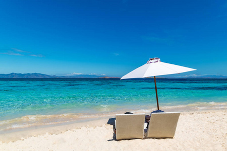 美丽的海滩。日光浴在海边的沙滩上带着雨伞。暑假和假期的概念。鼓舞人心的热带海滩