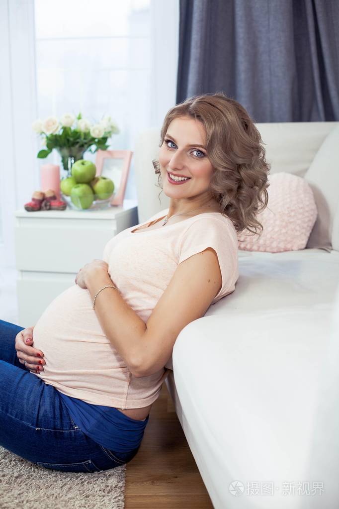 年轻漂亮的孕妇在家休息舒适一个年轻的女人站在窗边怀孕母亲