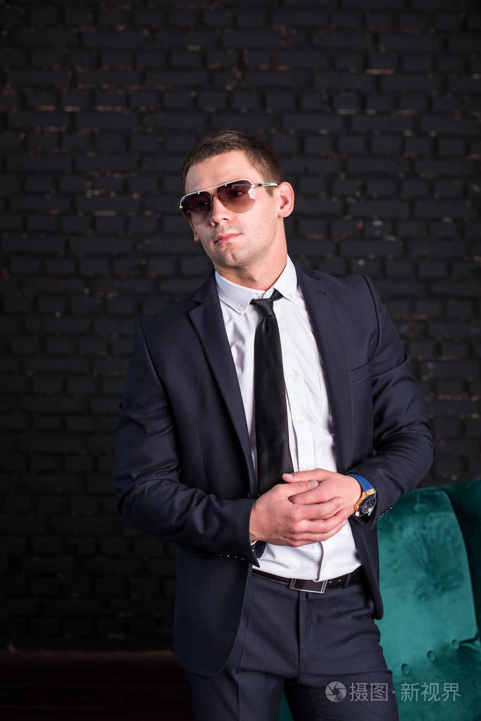 英俊的男人穿着西装对付黑砖墙, 模特照片.成功的时髦的人