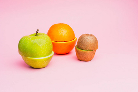 半切果 绿色苹果, 橙色和猕猴桃在柔和的粉红色背景