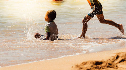 亚洲男孩愉快的乐趣在海滩海旅行玩