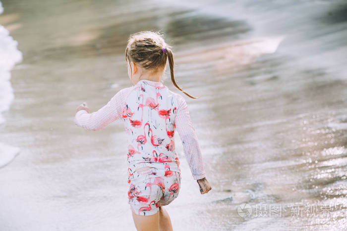 可爱的小女孩在沙滩漫步