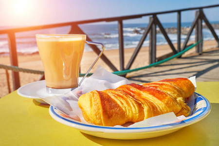 咖啡杯, 桌上有牛角面包, 有波浪的海景