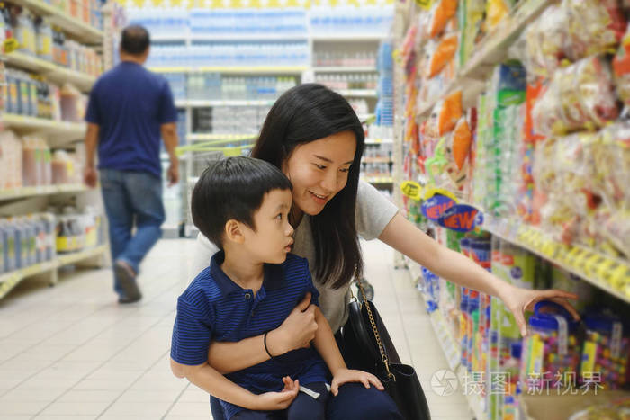 年轻的亚洲母亲和她的孩子在超级市场购物与模糊