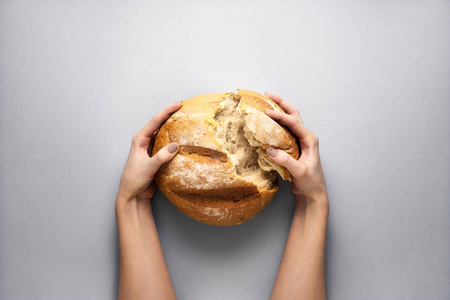 在灰色背景下手捧面包的创意概念照片