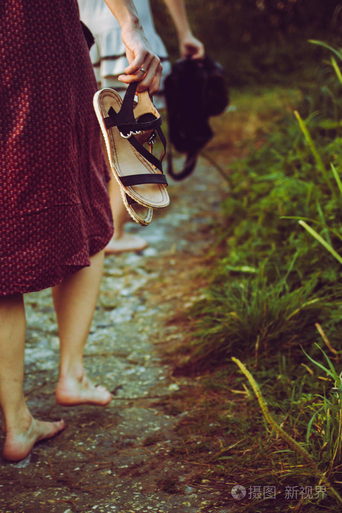 赤脚穿衣服的女人手里拿着鞋子后视图
