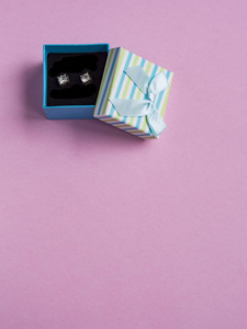 粉红色背景礼品盒中的耳环