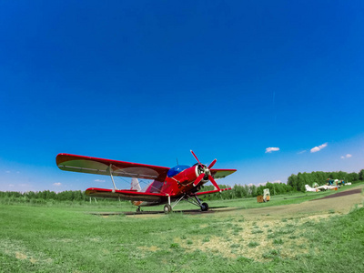一架小红色运动红色飞机在一个覆盖的草地上的苏
