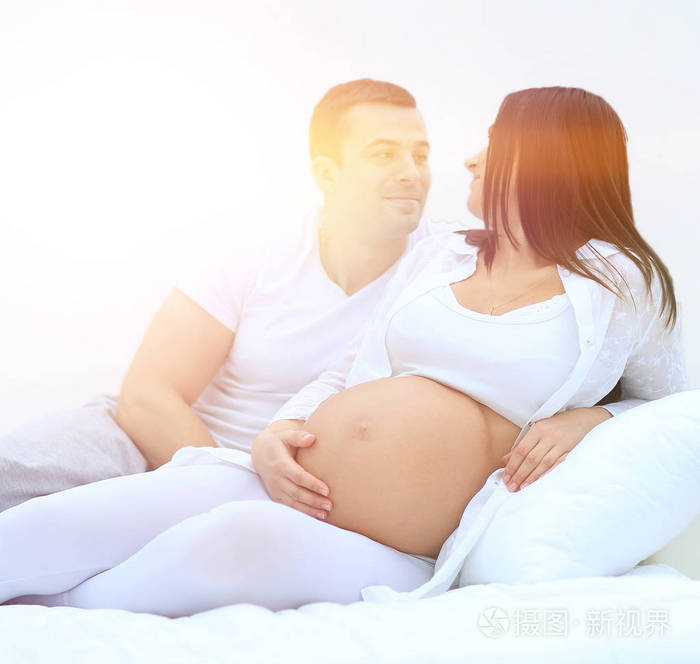 丈夫和怀孕的妻子躺在卧室的床上