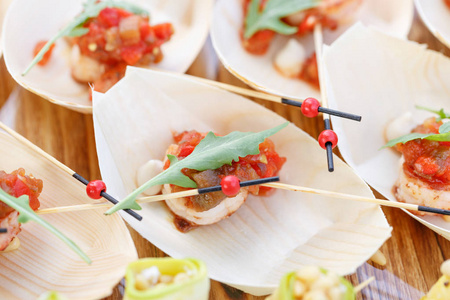 美味的虾和切片的西红柿在一艘木船上。美味的自助餐桌。夏季聚会室外。餐饮理念