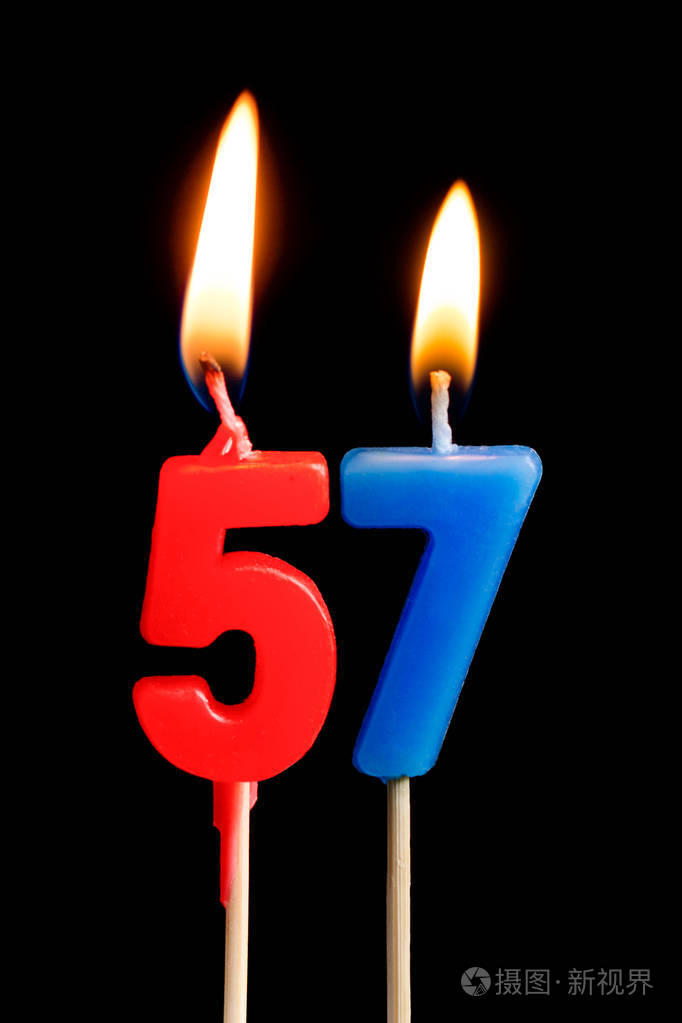 燃烧蜡烛的形式为56五十六数字日期的蛋糕孤立的黑色背景庆祝生日周年