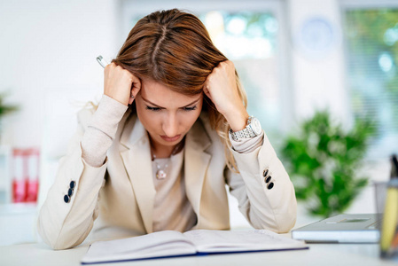 看文件沮丧的年轻女商人坐在办公室和苦恼看文件照片