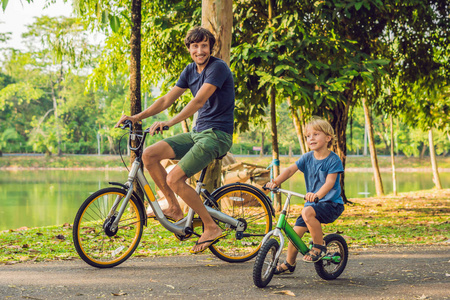 父亲和儿子骑自行车户外和微笑