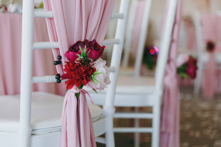 美丽的装饰婚礼宴会下的遮阳篷, 粉红色, 勃艮第和白色色调。用薄布装饰的白色宴会椅和餐桌旁的胸花花