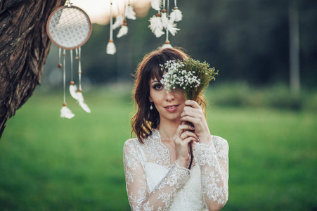 美丽的白种新娘在婚礼礼服与花束摆在面前的 dreamcatchers