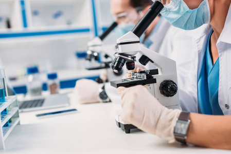 科学家在医学面具和护目镜中的选择性聚焦实验室中的董事看显微镜