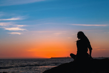 瑜伽女人的剪影在海洋在惊人的日落的冥想