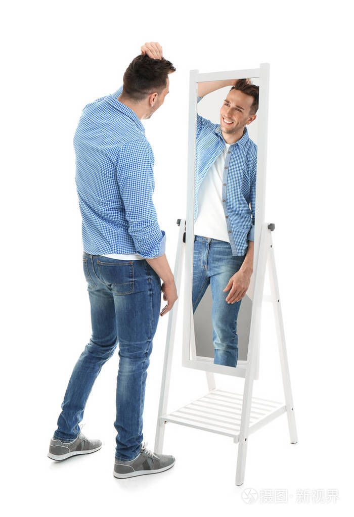 年轻男子看着自己在镜子上的白色背景