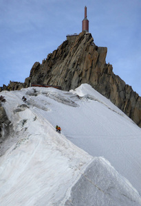 山指南和顾客降下一个狭窄的雪脊从山山顶在法国阿尔卑斯接近的