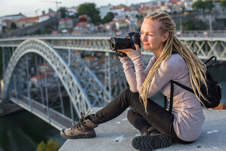 年轻女子与相机坐在观看平台对面的 Dom 路易斯大桥横跨杜罗河河, 波尔图, 葡萄牙
