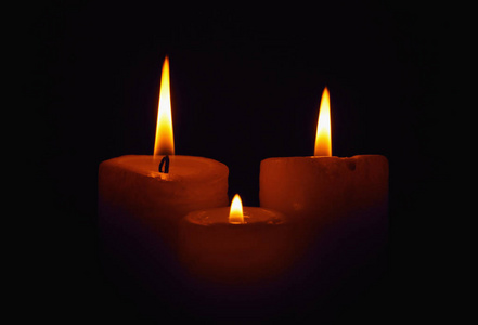 三个燃烧的蜡烛在黑暗中