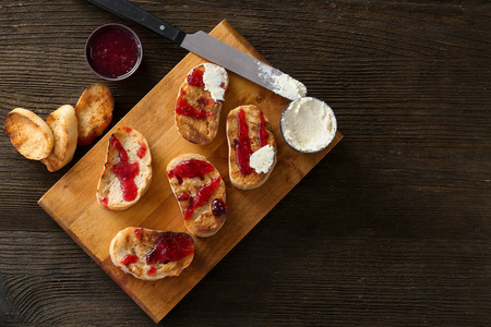 烤面包与果酱和奶油奶酪在木板上, 顶部视图