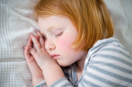 那个面色红润的女孩用双手折叠在脸颊上睡觉。