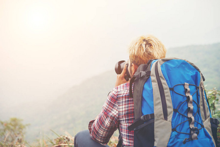 罕见的年轻旅行男子与背包站在山上拍照。男性徒步旅行者拍摄美丽的山地景观