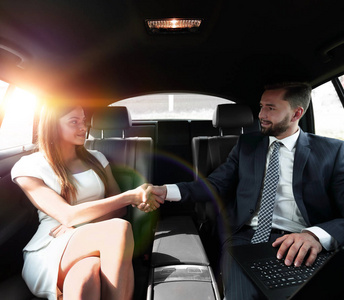 美丽的夫妇在汽车中使用的膝上型计算机