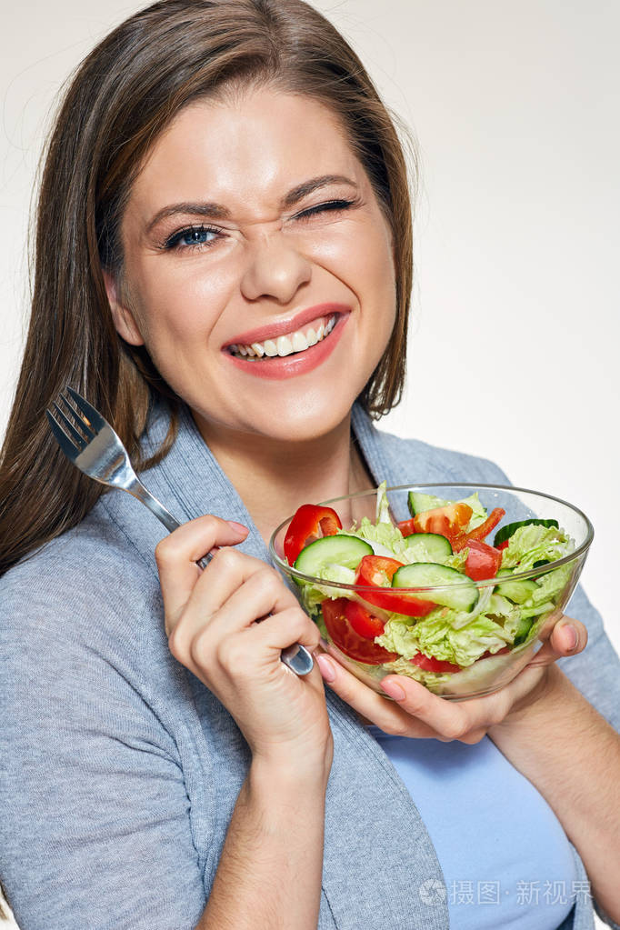年轻的微笑的妇女拿着蔬菜沙拉玻璃碗独立肖像