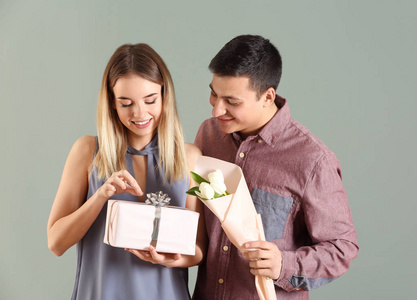 年轻人送礼物和花给他心爱的女朋友在颜色背景