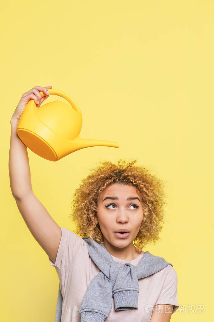 她手上拿着一个水壶.她准备给她的头发倒点水.女孩在看边.