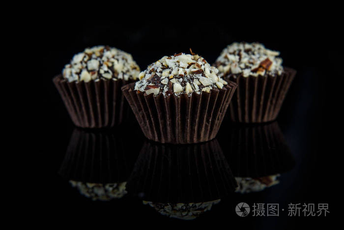 三大巧克力糖果在黑色镜子背景下反射