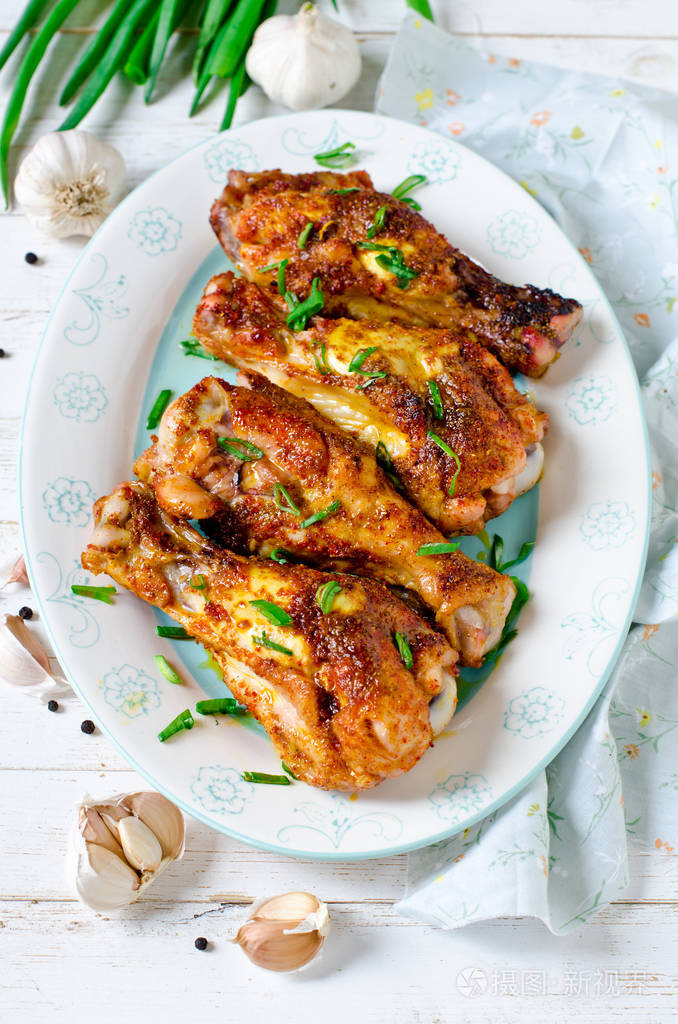 烤鸡腿放在白色木桌上的盘子上