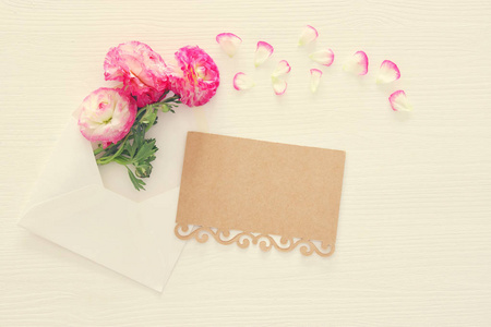 图像的信封与微妙的粉红色美丽的花朵安排在白色的木质背景。平躺, 顶部视图。复古过滤