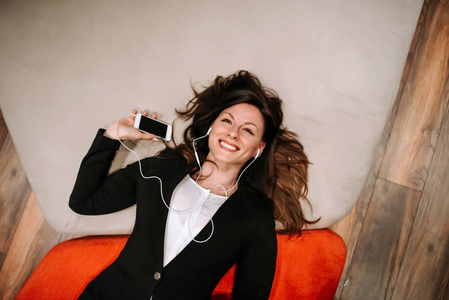 微笑商务女性的顶级视图躺在电话里听音乐