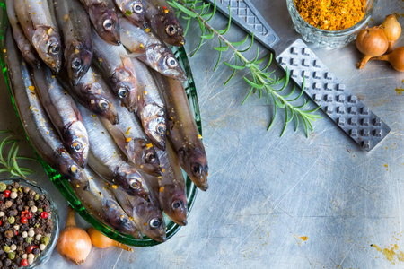 新鲜鱼顶视图。辛辣的药草和蔬菜。在金属桌上的鱼和香料。健康食品烹饪
