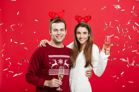 圣诞概念快乐的白种人和女人在驯鹿帽子庆祝圣诞节与香槟长笛敬酒, 祝贺圣诞