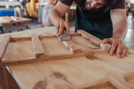在他的大型木工车间工作时, 熟练木匠手打磨木制家具设计的特写