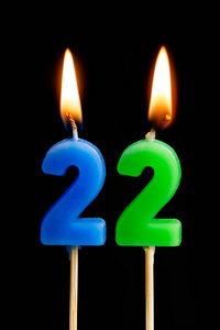 燃烧蜡烛的形式为22二十二 (数字, 日期) 的蛋糕孤立的黑色背景.