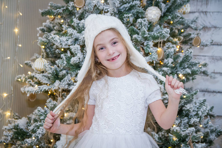圣诞树下戴白帽子的女孩