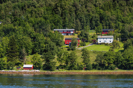 典型的斯堪的纳维亚风景与草甸和村庄。有红色墙壁和屋顶的房子, 草坪。挪威