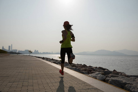 运动的年轻健身妇女运行在日出海岸小径