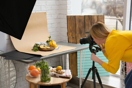 在专业工作室拍摄柠檬, 薄荷和生姜图片的年轻女子。食品摄影