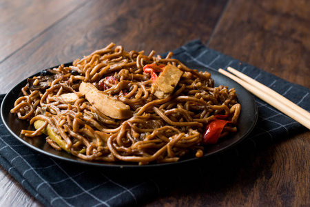 黑盘子里有豆腐和红辣椒的素食面条