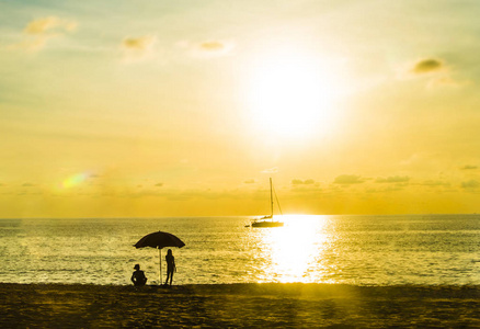 日落时分在海滩上享受度假的人们的剪影