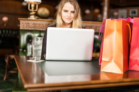 在网上为节日礼物在互联网上微笑的年轻女性商店星期一与礼物在袋子